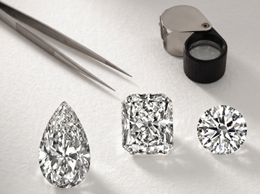 Pear, radiant, and round loose diamonds with jeweler's tweezers and loupe